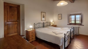Ein Schlafzimmer mit zwei Betten, Holzmöbeln, einem Fenster mit Aussicht und einer Decke mit sichtbaren Balken.