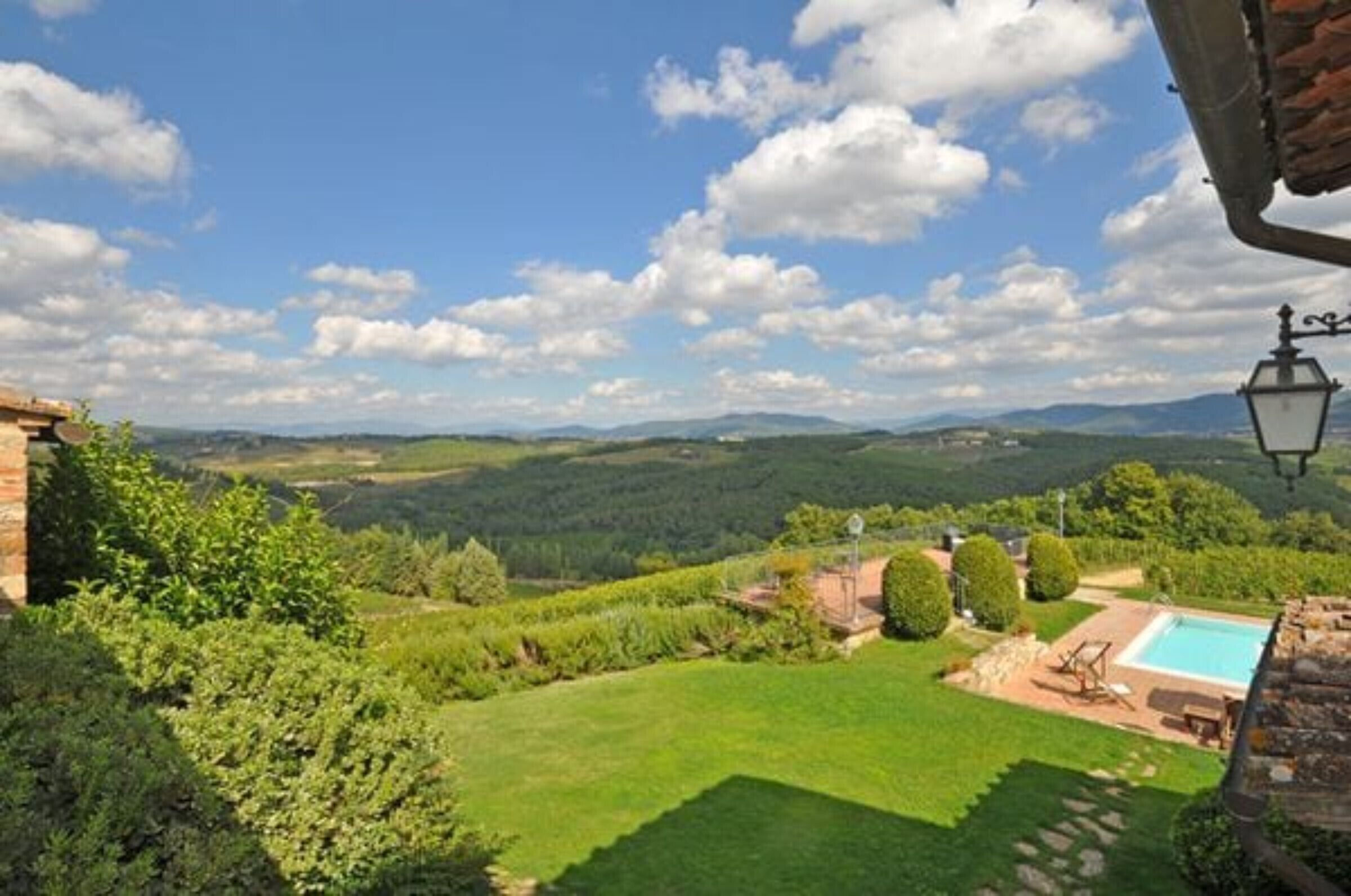 Blick auf ein Anwesen mit Schwimmbad, Rasen und Bergen im Hintergrund.