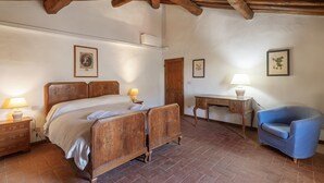 A bedroom with a wooden bed, a desk, a chair, and a lamp. - Tenuta Branca - Podere Apartment with Pool and Terrace in Chianti (San Casciano in Val di Pesa)