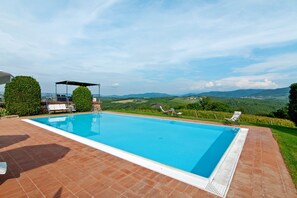 A rectangular swimming pool with a clear blue water surface, surrounded by a tiled deck. - Tenuta Branca – Torrione Spacious Apartment with Pool in Chianti (San Casciano in Val di Pesa)