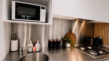 Une cuisine moderne équipée d’un évier en acier inoxydable, d’un four à micro-ondes et d’une cuisinière à gaz.