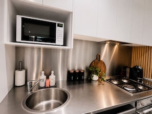 Una cocina moderna con un lavamanos de acero inoxidable, un microondas y una estufa a gas.