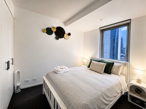 Une chambre à coucher moderne avec un lit, des tables de chevet, une fenêtre et un élément décoratif fixé au mur.