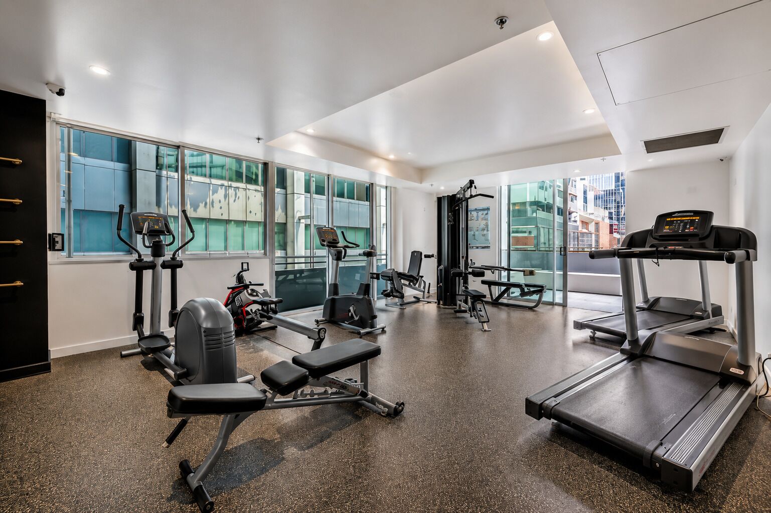 Een fitnessruimte met cardioapparatuur, krachttoestellen en banken.