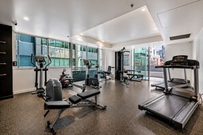 Une salle de sport équipée de machines de cardio, de postes d’entraînement avec poids et de bancs.