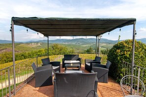 A covered outdoor seating area with wicker furniture and a view of the countryside. - Tenuta Branca – Voltine Apartment: Comfort and Pool in Chianti (San Casciano in Val di Pesa)