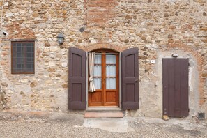 A stone building with a wooden door, a window, and a small step leading to the entrance. - Tenuta Branca – Voltine Apartment: Comfort and Pool in Chianti (San Casciano in Val di Pesa)