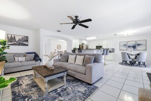 A modern living room with a grey sofa, a coffee table, and a ceiling fan. - Nr Sea World Hot Tub Game Room Yard Swing Set BBQ (San Antonio)