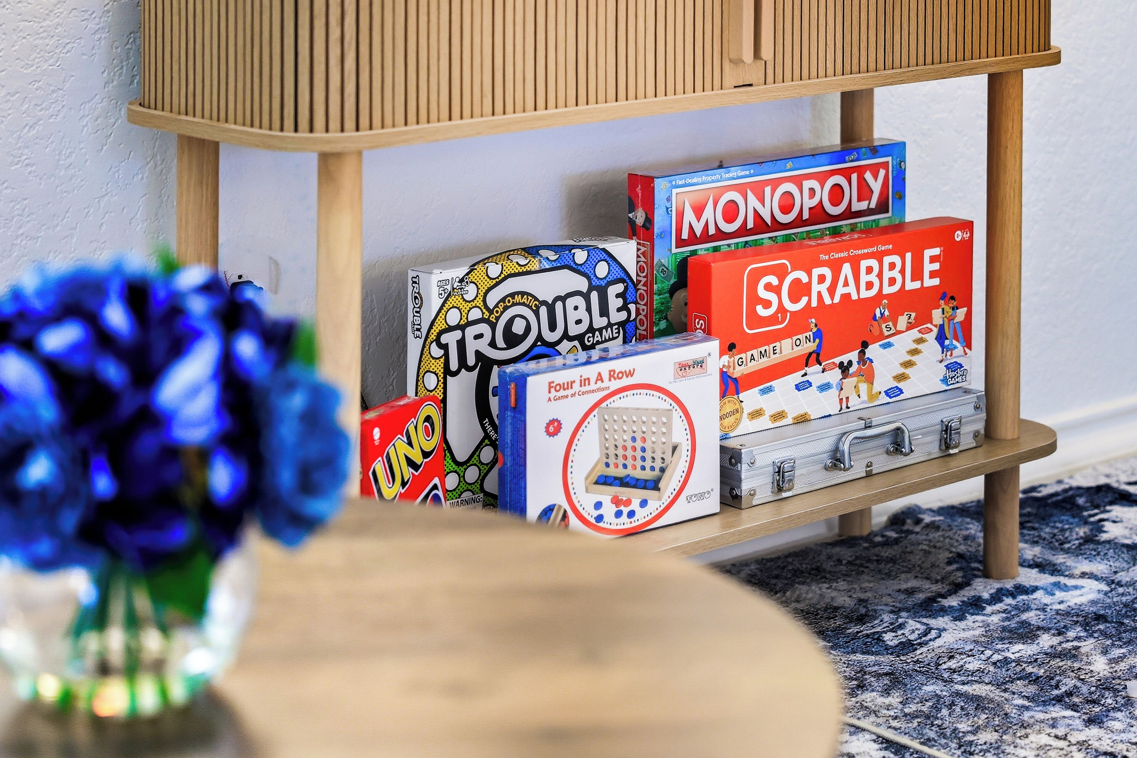 Una estantería con juegos de mesa como Monopoly, Scrabble y Trouble.