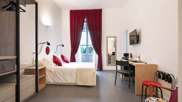 Une chambre moderne comprenant un lit, un bureau et une chaise, une armoire et une fenêtre avec des rideaux.