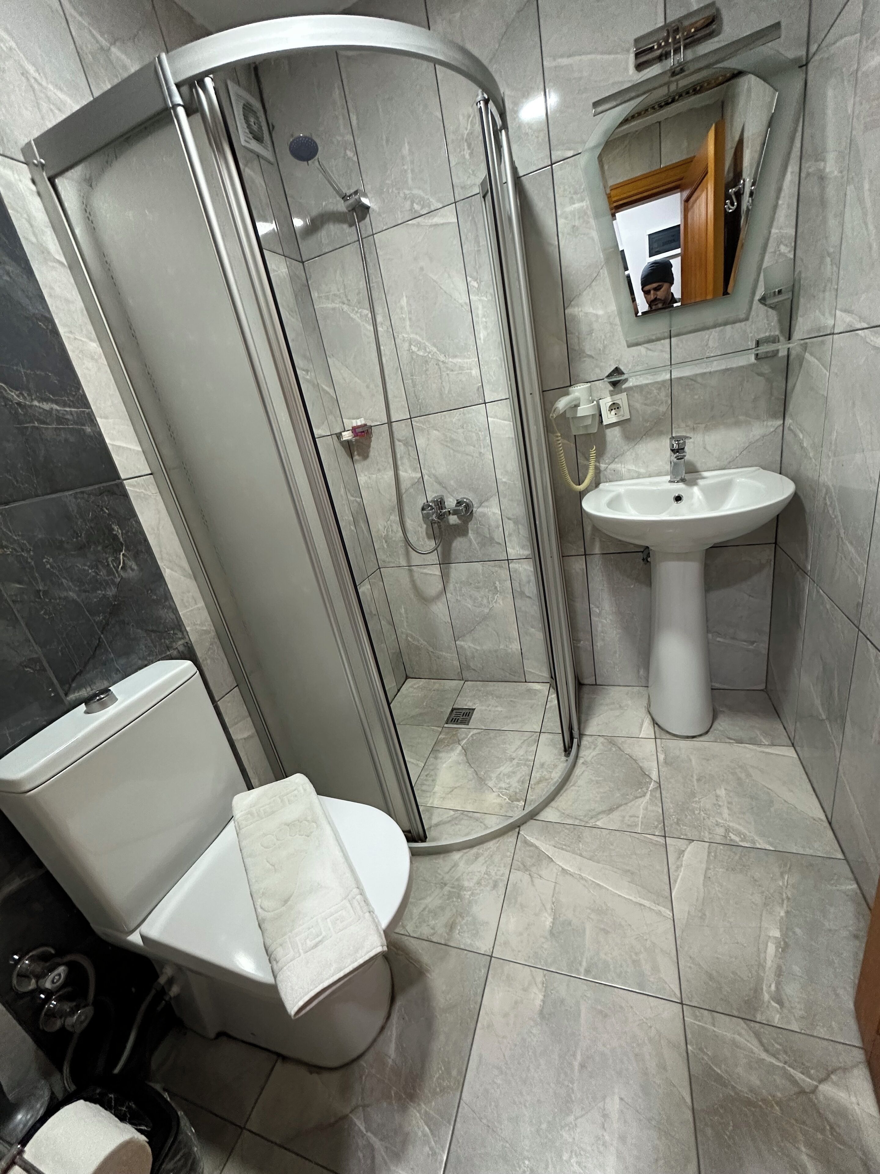 Une salle de bain moderne avec une douche à parois de verre, un lavabo sur colonne et des toilettes.