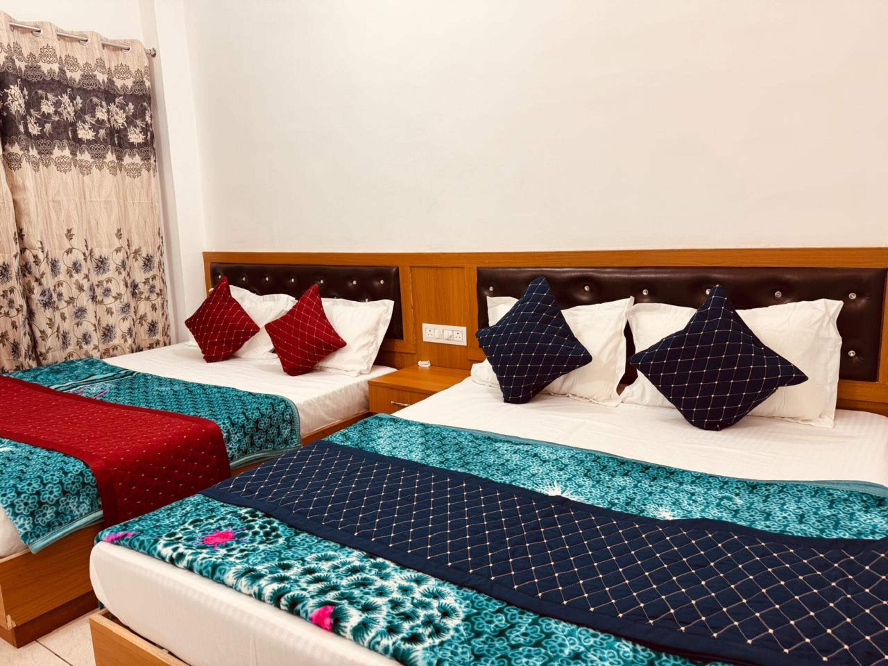 Quarto de hotel com duas camas, cada uma com cabeceira de madeira, roupa de cama branca e almofadas decorativas.