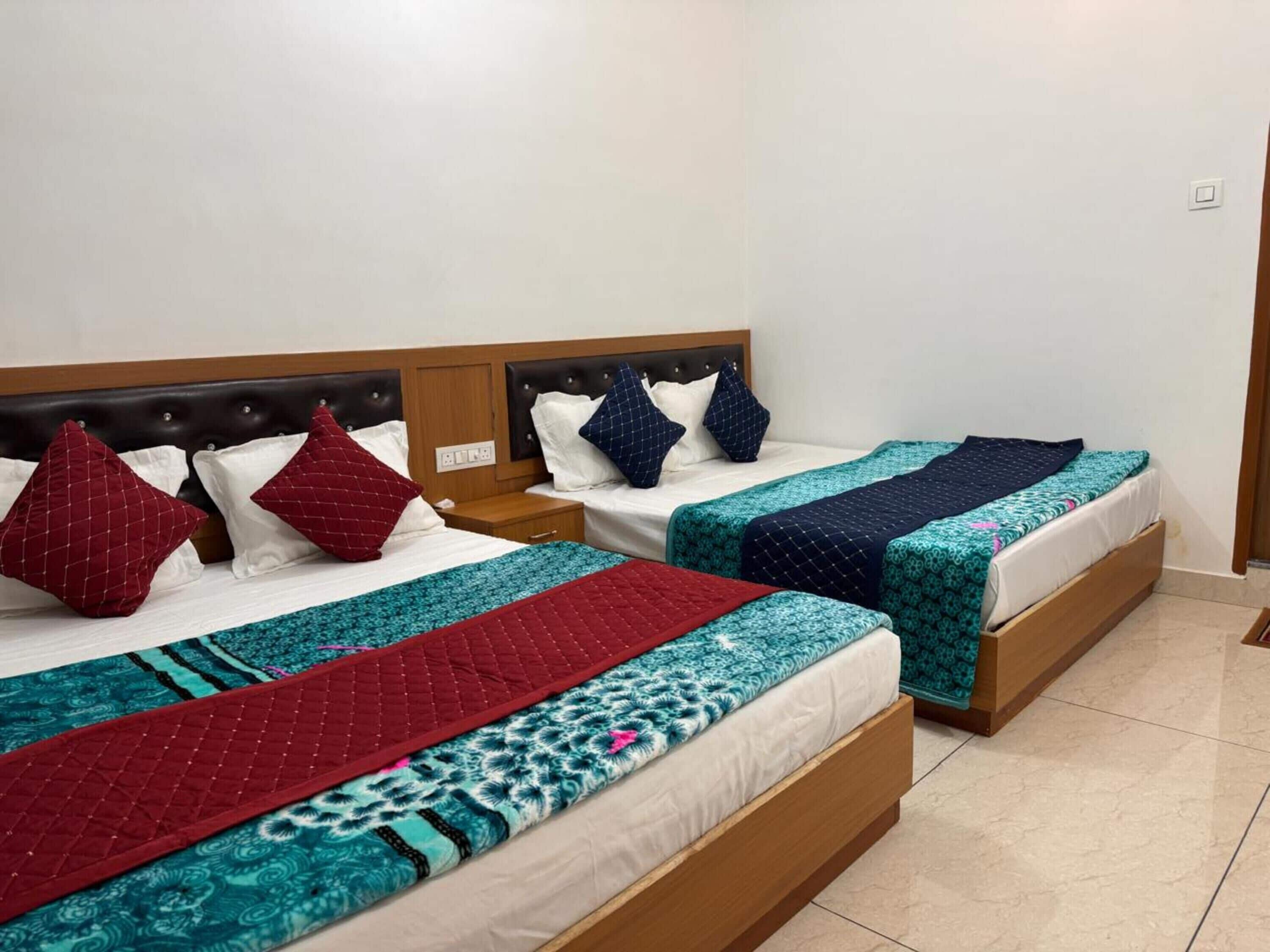 Habitación de hotel con dos camas, cada una con cabecera, mesitas de noche y varios almohadones.