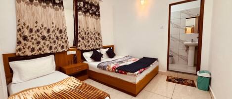 A bedroom with two beds, a nightstand, a mirror, and a bathroom visible through an open door.