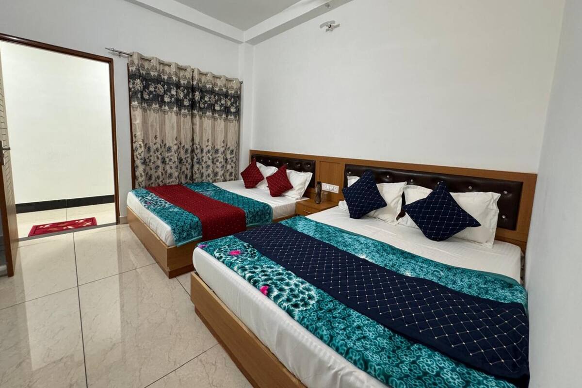 Une chambre d’hôtel avec deux lits, chacun doté d’une tête de lit en bois, d’une couvre-lit à motifs rouges et bleus, et d’oreillers assortis.