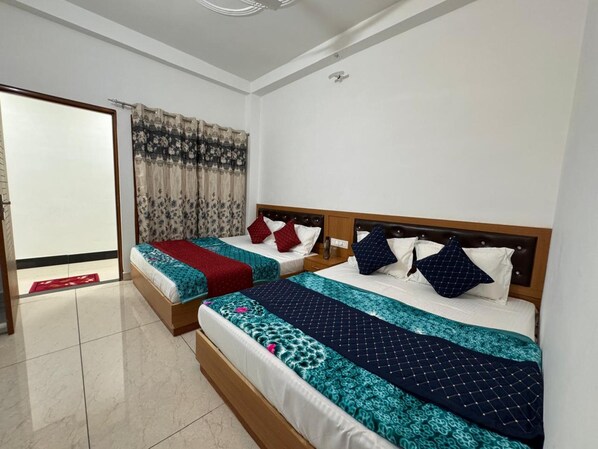 Une chambre d’hôtel avec deux lits, chacun doté d’une tête de lit en bois, d’une couvre-lit à motifs rouges et bleus, et d’oreillers assortis.
