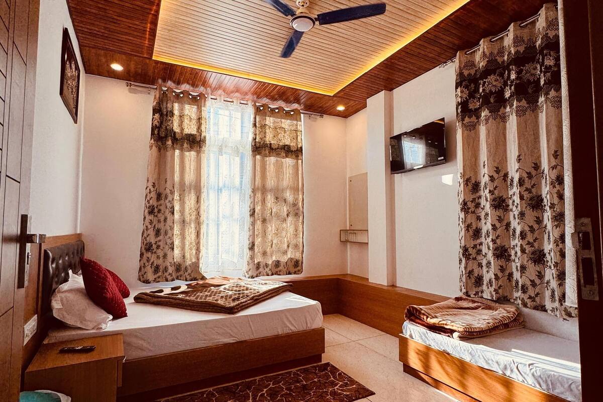 Une chambre à coucher avec un lit, un ventilateur de plafond et un téléviseur fixé au mur.