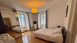 Een slaapkamer met een bed, een stoel, een televisie en een spiegel.