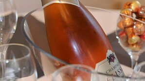 Een champagnefles met etiket, geplaatst op een tafel met glazen en een dessert.