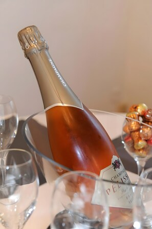 Eine Flasche Champagner mit Etikett auf einem Tisch mit Gläsern und Dessert.