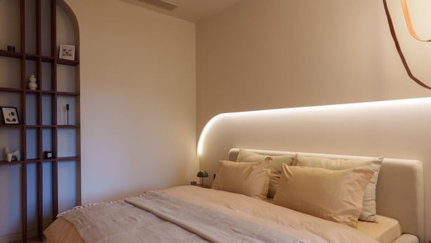 A bedroom with a bed, a bedside table, a lamp, a shelf with decorative items, and a wall-mounted light. - Designer suites on Mashtots avenue (Yerevan)