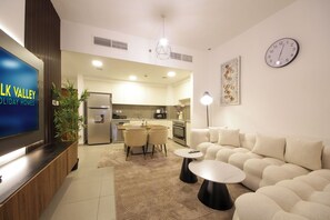 Un salon moderne doté d’un téléviseur à écran plat, d’un canapé, d’une table basse et d’un coin repas avec des chaises.