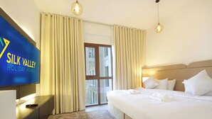 Una camera d'albergo con un letto, una TV, tende e vista all'esterno.