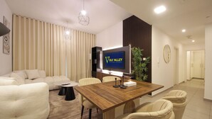 Un soggiorno moderno con un tavolo da pranzo in legno, divani beige e un televisore a schermo piatto.
