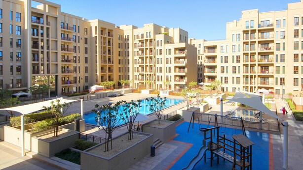 Un edificio residenziale con diversi balconi, una piscina e un'area giochi.