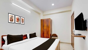 A hotel room with a large bed, a wardrobe, a television, and framed artwork on the wall. - Super Hotel O Sadar Bazar Gurgaon (Gurugram)