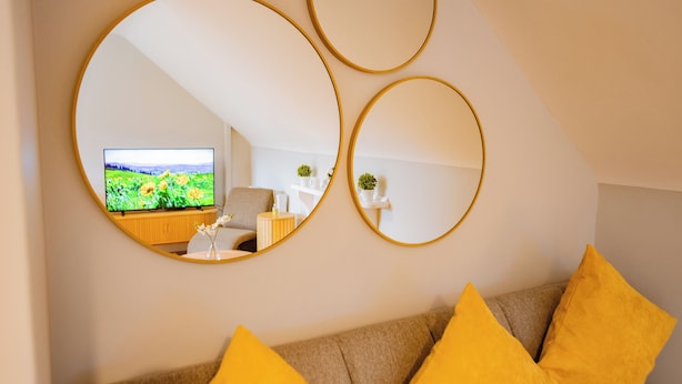 Ein Wohnzimmer mit einer Couch, gelben Kissen und drei runden Spiegeln an der Wand.