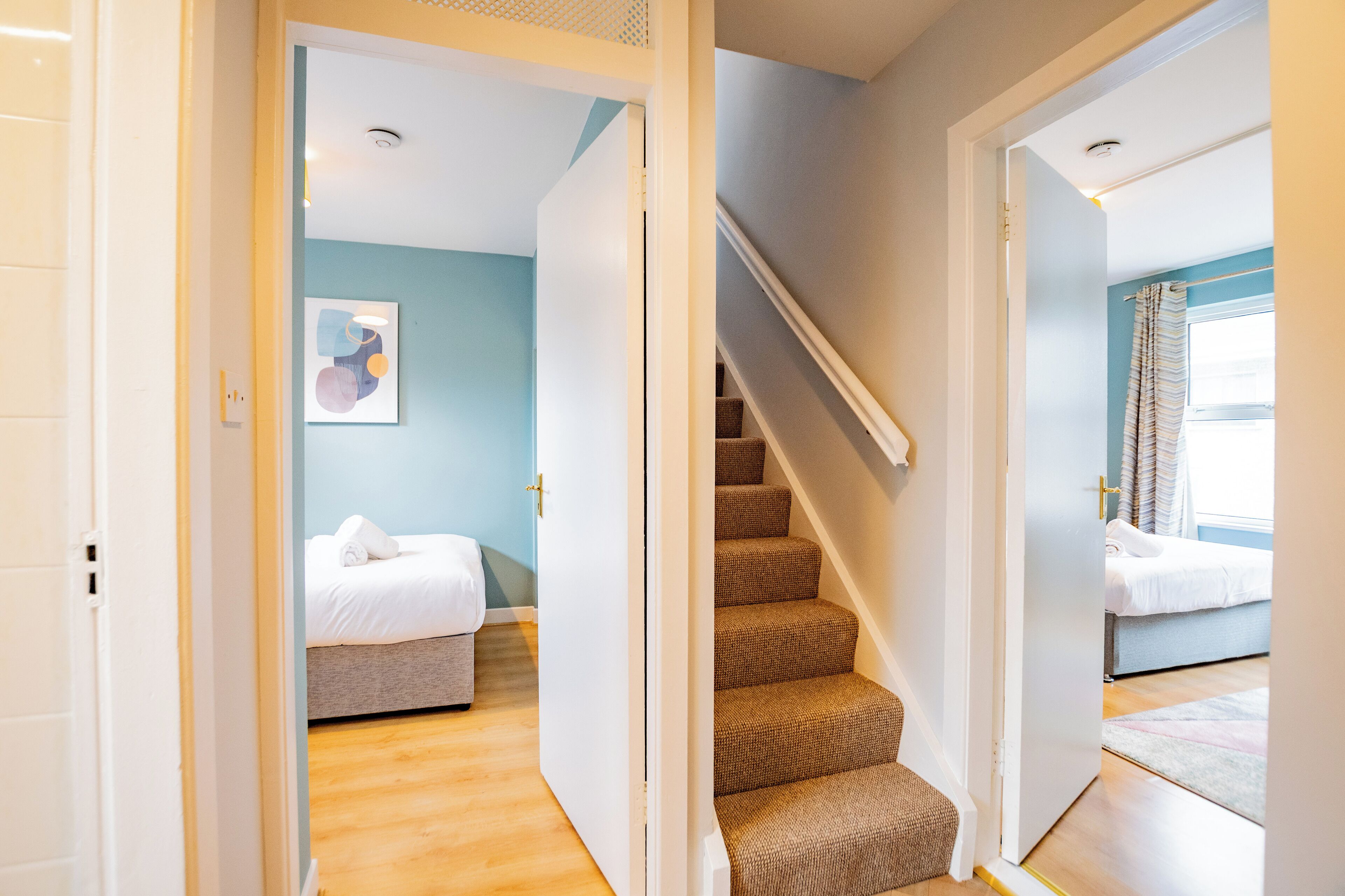 A hotel room with a bed, a staircase, and a view of another room.