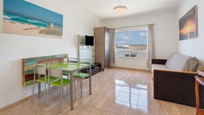 Ein modernes Wohnzimmer mit Essbereich, Fernseher, Sofa und großem Fenster mit Aussicht.
