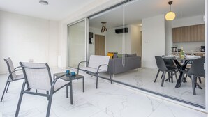A modern living space with a glass partition separating the dining area from the living area. - Mirage 2-BR Apt. & Balcony in Larnaca (Larnaca)