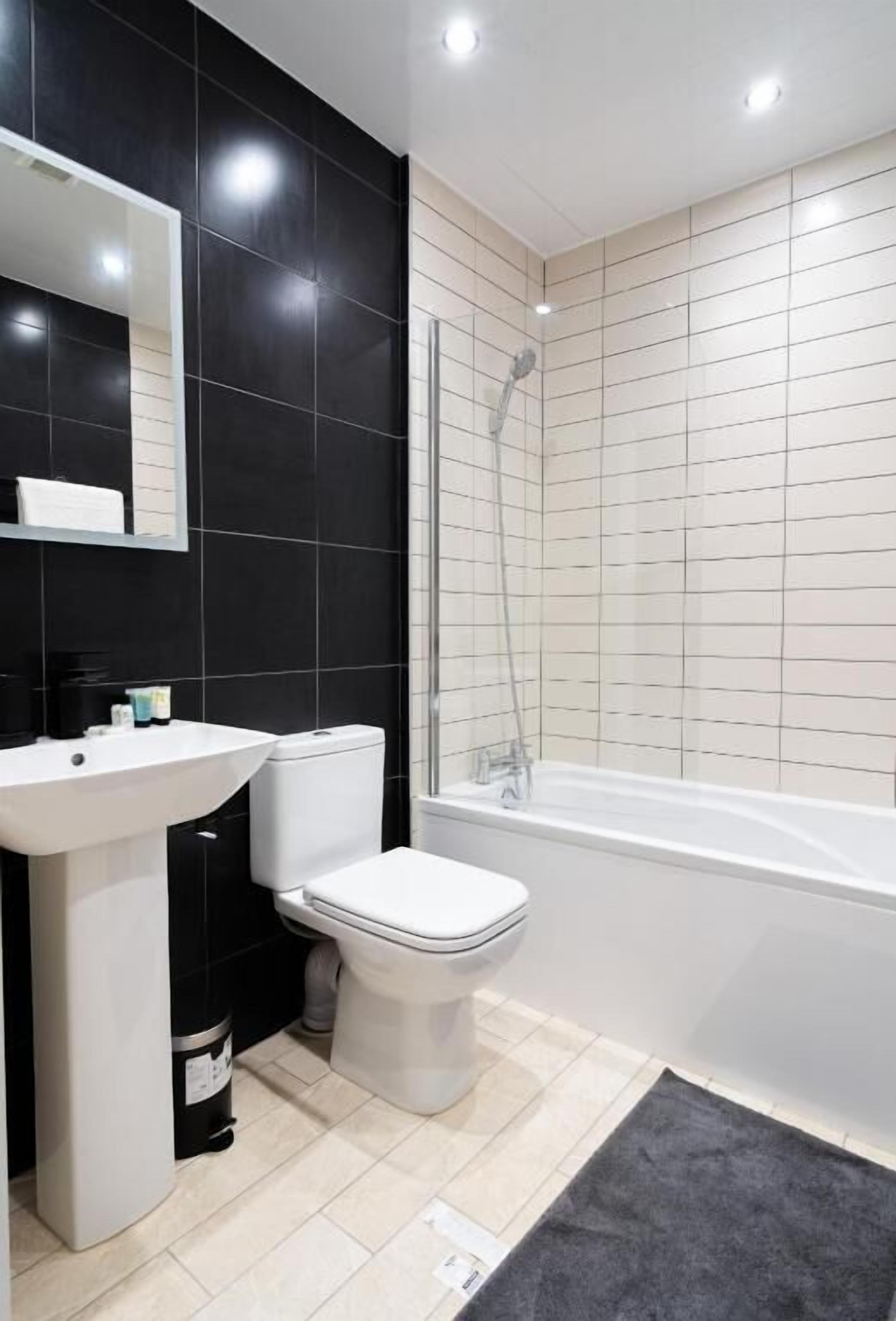 A modern bathroom with a white sink, toilet, and bathtub.