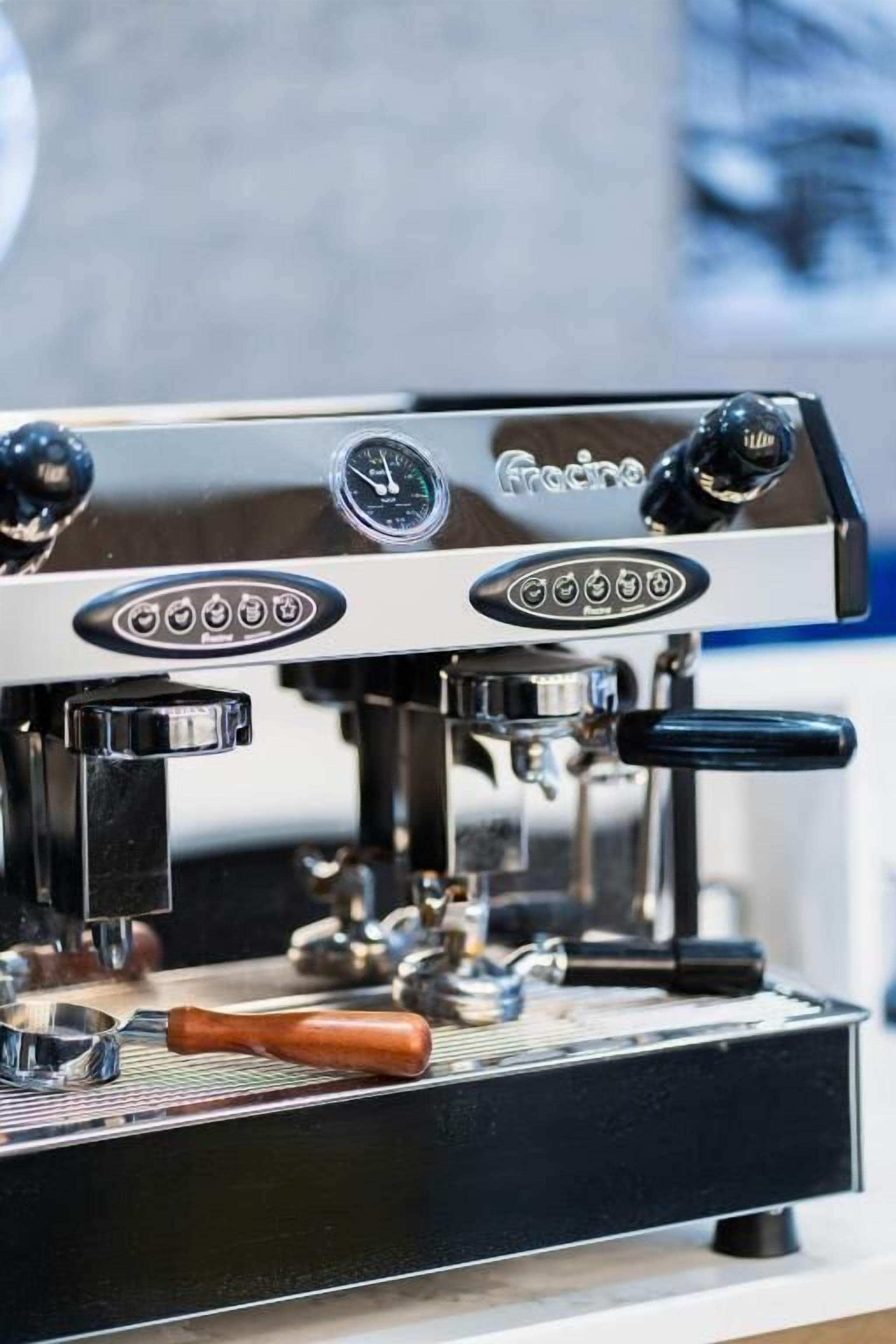 Primer plano de una máquina de espresso profesional con varios botones de control y una pantalla digital.
