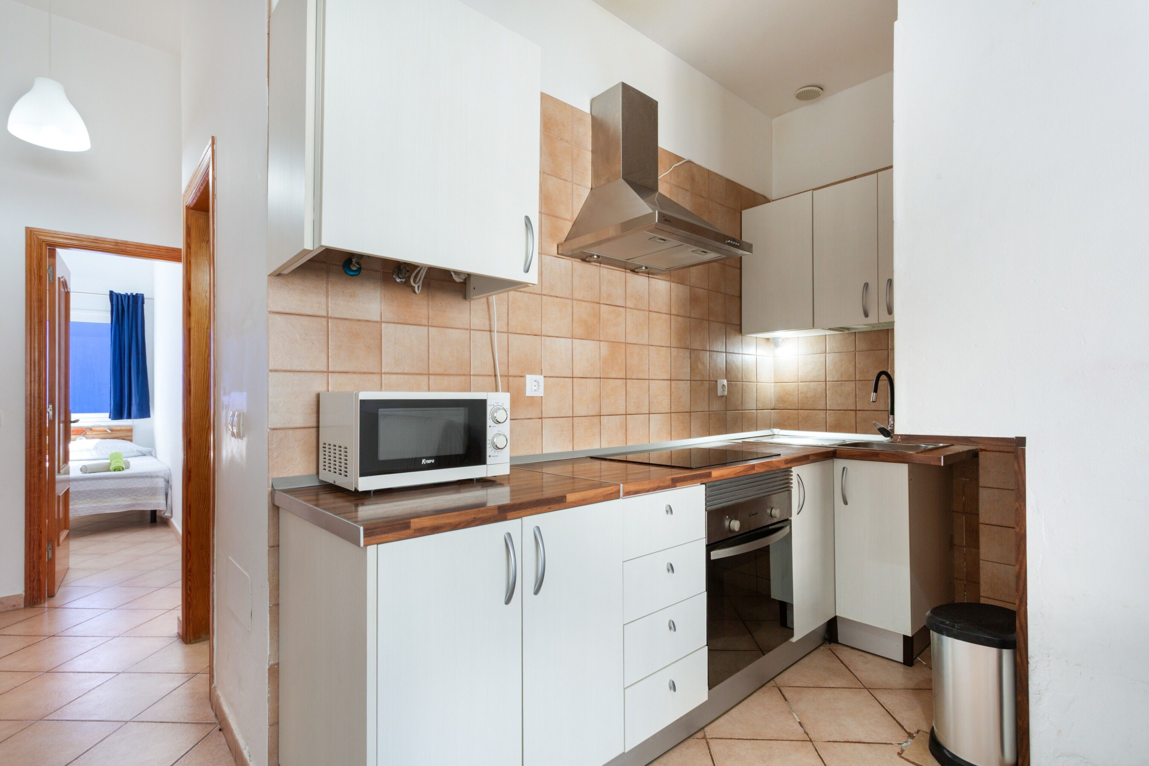 Una cocina moderna con armarios blancos, microondas y una campana extractora de acero inoxidable.