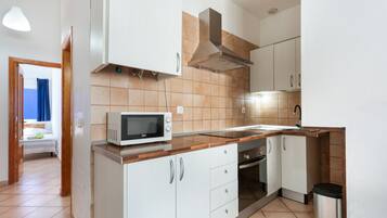 Una cocina moderna con armarios blancos, microondas y una campana extractora de acero inoxidable.