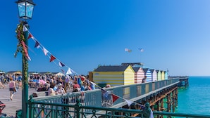 A pier with colorful beach huts and a crowd of people. - 1066 Apart Hotel (Hastings)