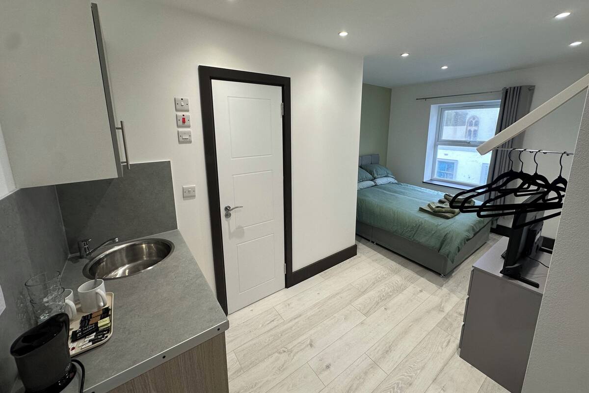 Habitación de hotel compacta con kitchenette, una cama, ventana con vistas y una escalera.