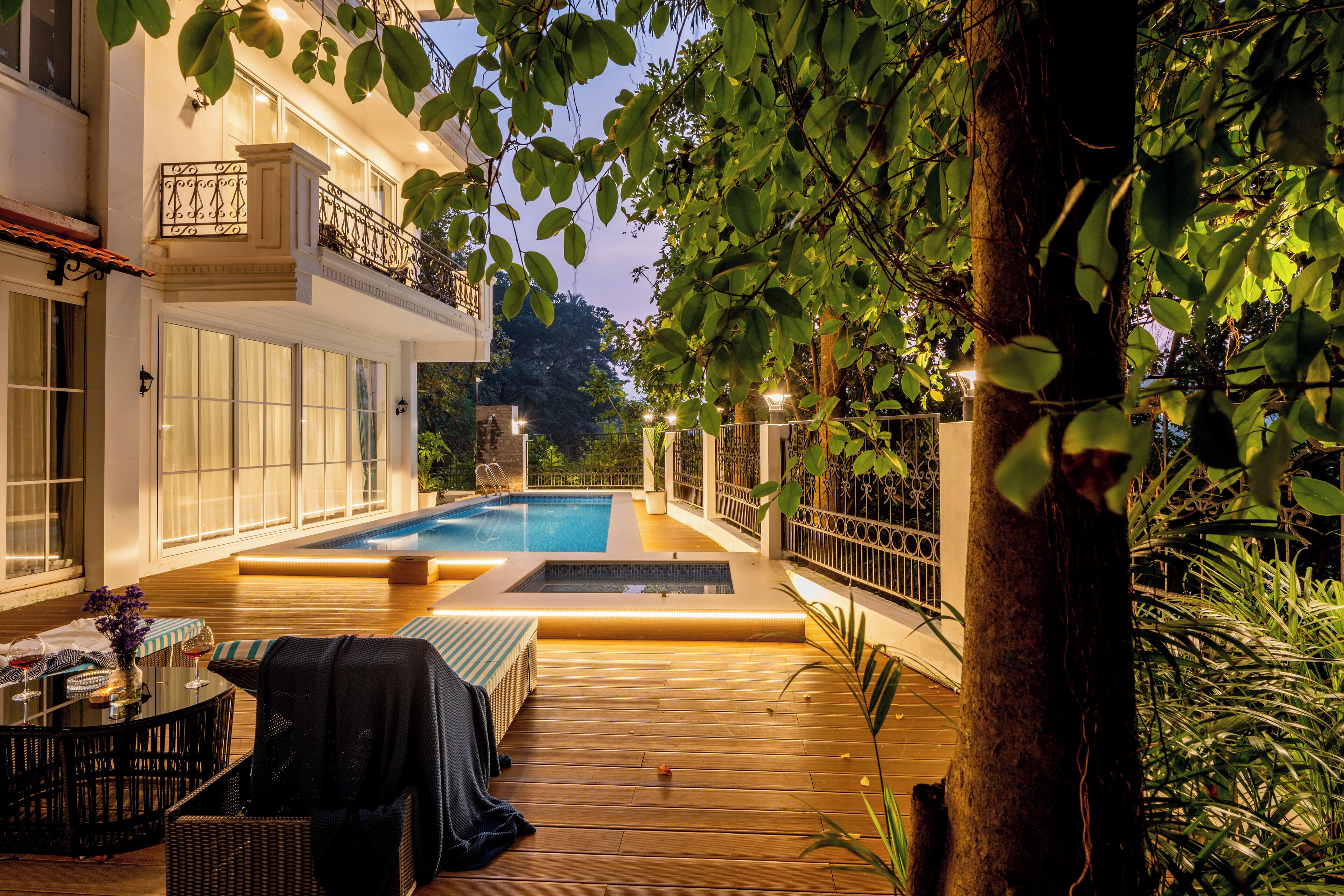 Un área de piscina con terraza de madera, sillas de descanso y una mesa de comedor con decoración para exteriores.