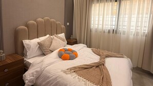 Un dormitorio ordenado con una cama grande, una mesita de noche y una ventana con cortinas.