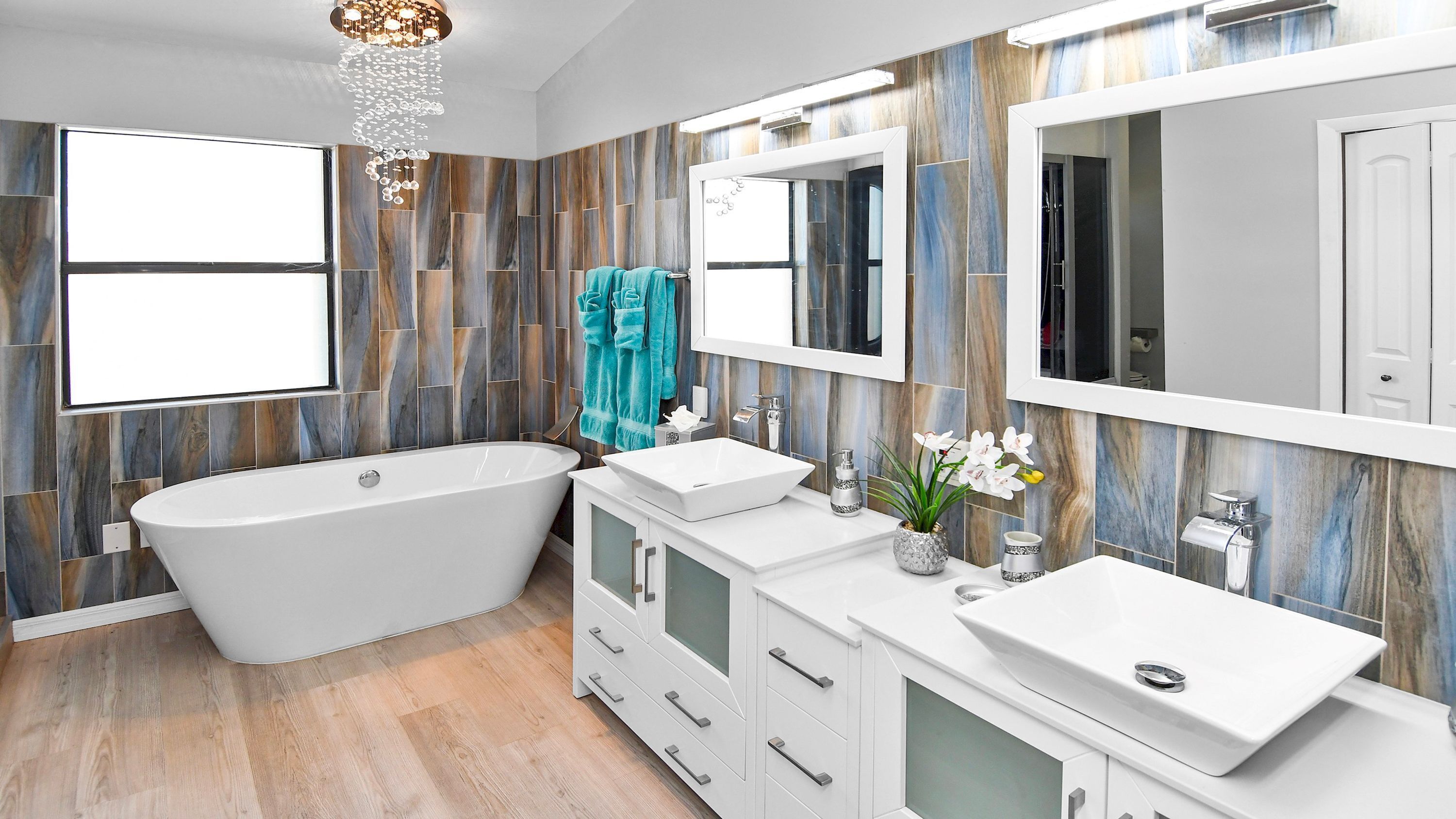 A modern bathroom with a freestanding bathtub, a vanity with two sinks, and a large mirror above the vanity.