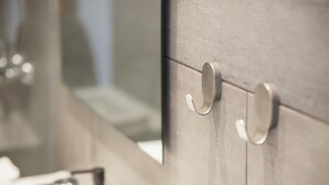A bathroom vanity with a mirror, two metallic handles, and a soap dispenser. - Comfy Apartment by Olala Homes  (Cascais)