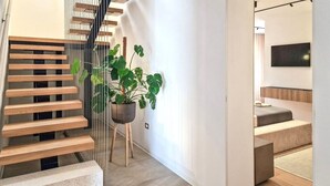 A modern staircase with wooden steps and a metal railing, leading to a room with a bed and a flat-screen TV. - Villa Corsa by Villas Guide (Barban)