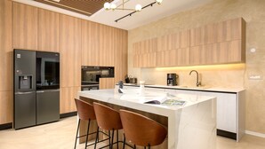 A modern kitchen with wooden cabinets, a black refrigerator, a microwave, and a coffee maker. There are three wooden bar stools at the island. - Villa Corsa by Villas Guide (Barban)