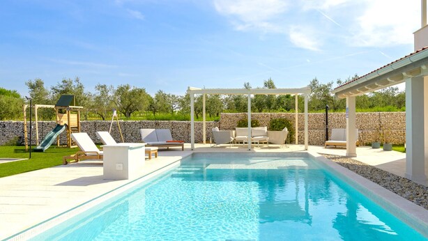 A swimming pool with lounge chairs and a children's play area. - Villa Corsa by Villas Guide (Barban)