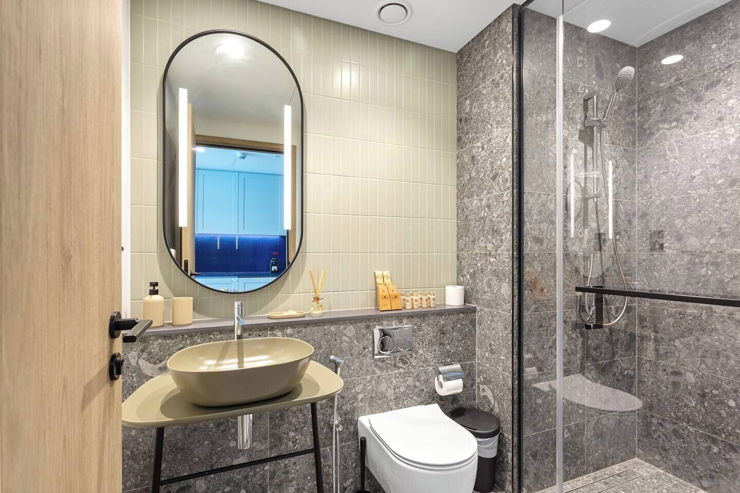 Un baño moderno con un espejo redondo, un lavabo, un inodoro y una zona de ducha.