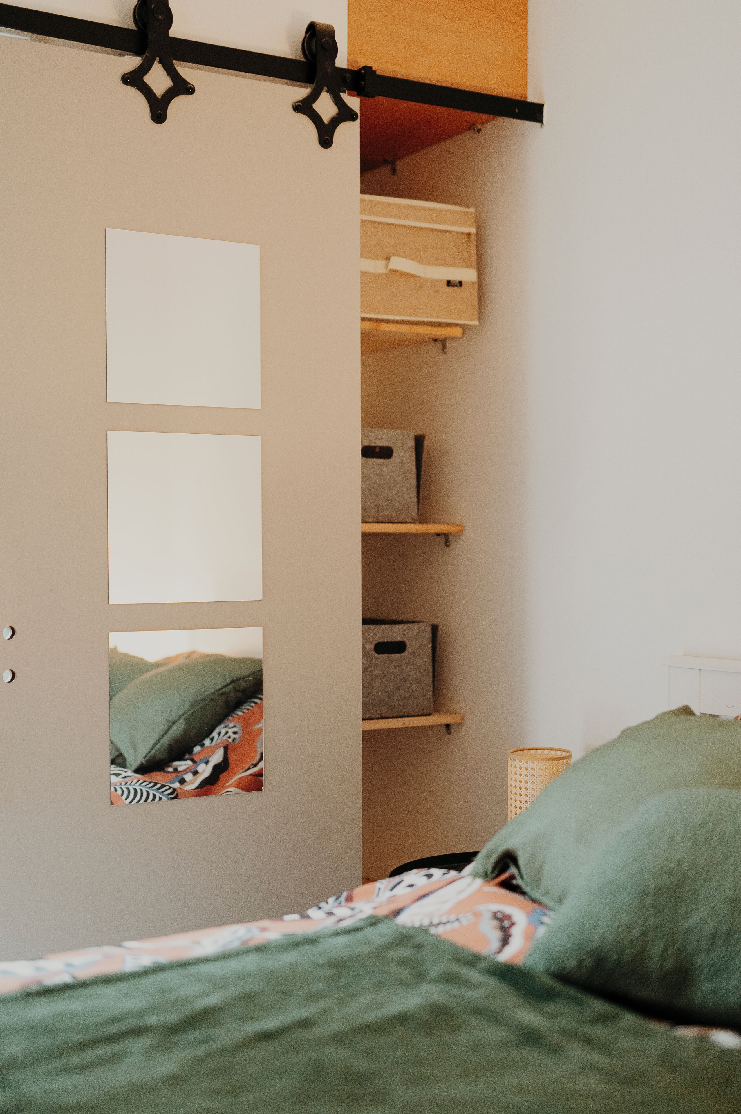Une chambre à coucher avec un lit, une armoire avec un miroir et des boîtes de rangement.