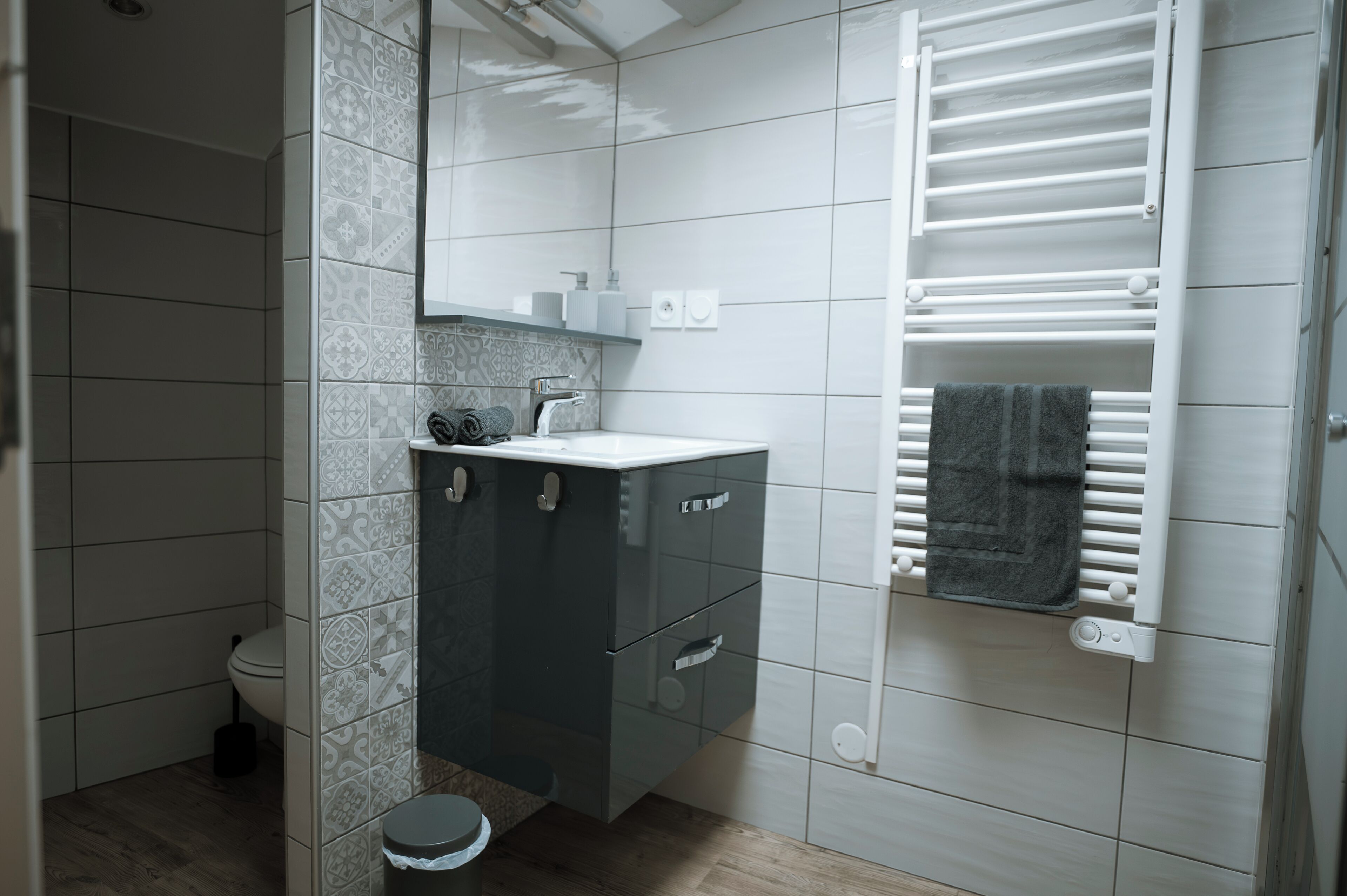 Un baño con un lavabo moderno, espejo y toallero.